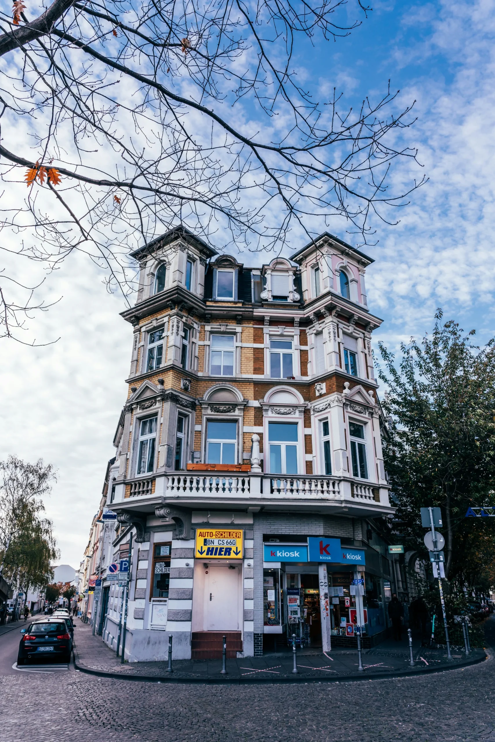 Mehrstöckiges Wohnhaus mit Laden im Erdgeschoss an einer Straße.