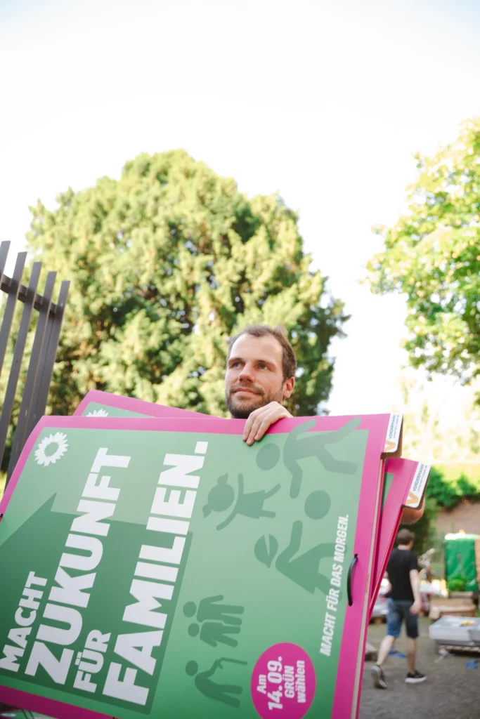 Eine Person trägt bei einer Veranstaltung ein großes Wahlplakat für Familien.